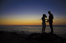 silhouette of a couple on a shore at sunset 