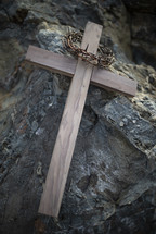 crown of thorns and wooden cross on a rock 