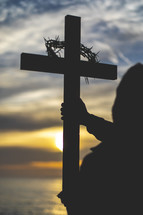 silhouette of a man holding a cross at sunset 