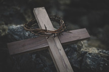 wooden cross with crown of thorns on a rock 