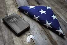 Folded American flag, dog tags, and Bible 