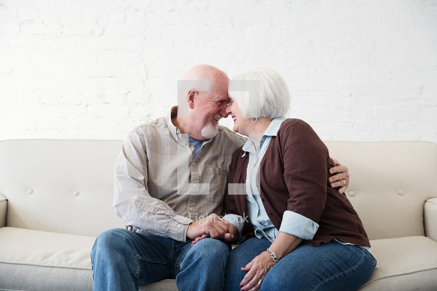 a happy, loving elderly couple snuggling on a couch 