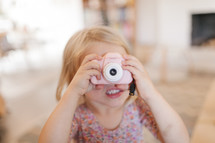 a toddler girl holding a camera 