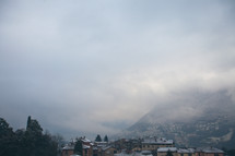 fog and thick clouds over roofs of homes in a valley 