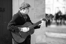 man playing a guitar on a street corner 
