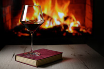 	Dry Glass Of Red Wine, on Book and Fireplace in Background
