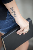 woman with a forgiven tattoo holding a Bible