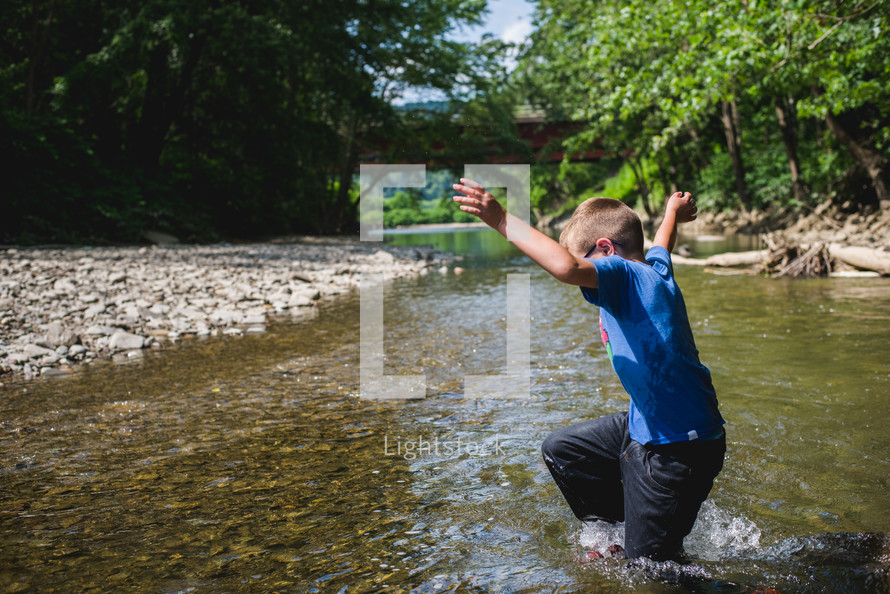 a little boy splashing in a river 