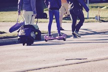 A girl on a hoover board riding down a street 