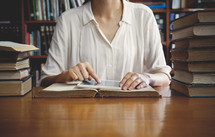 a woman reading sitting at a table in a library 