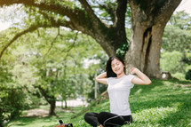 a young woman stretching listening to music in a park 