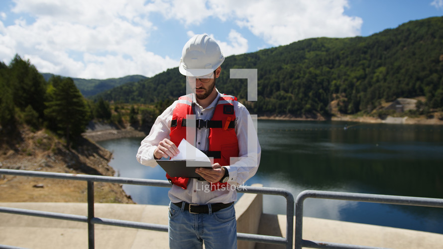 Man Construction manager with a notepad check the dam building on the mountains