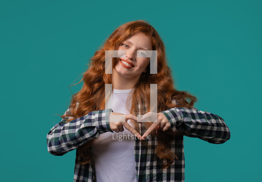 Smiling woman showing sign of shape heart. Positive lady on blue. Love. Women health, volunteering, charity donation, gratitude symbol, flirting concept. High quality photo