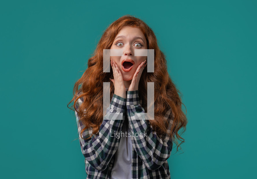 Surprised woman, she expresses WOW, cant believe. Impressed lady trying to get attention. Concept of sales, profitable offer. Excited ginger girl on blue background. High quality