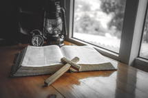 wooden cross in front of an open Bible 