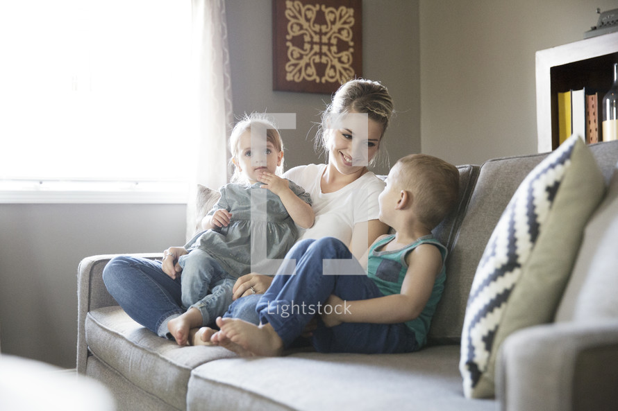 a mother sitting on the couch with her children 