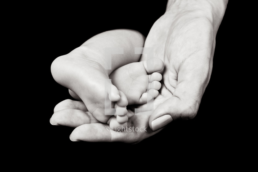 a mother's hand holding infant feet