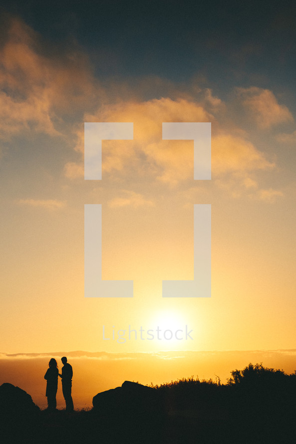 silhouettes of people standing on a mountaintop at dawn 