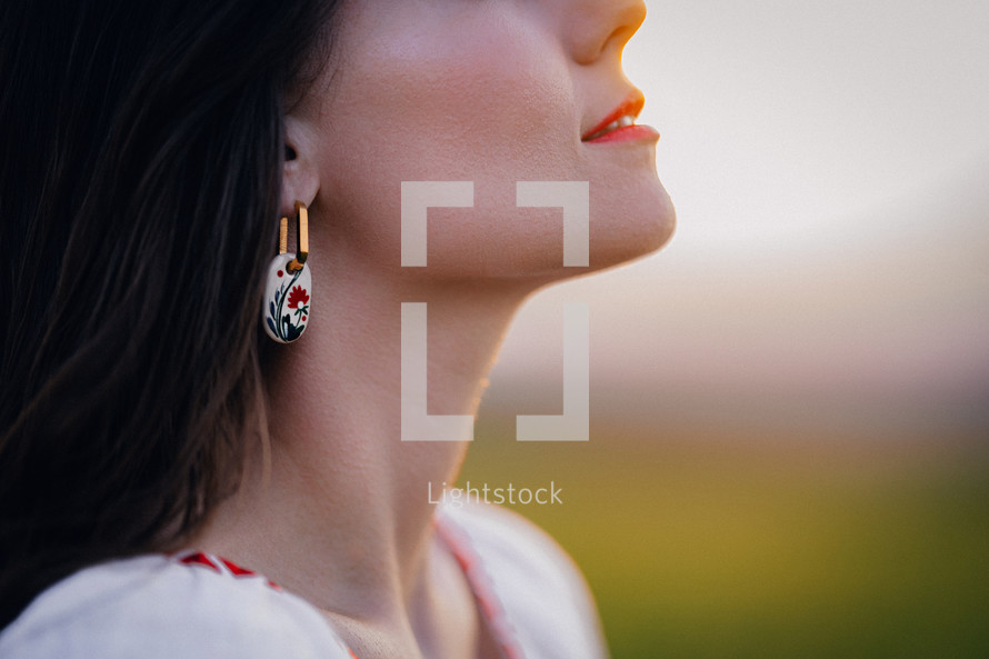 Young woman with ethnic earring and shirt with traditional ornaments breath free