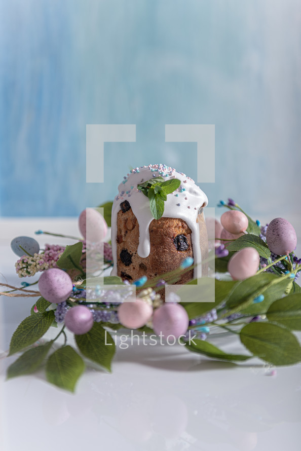 Easter cake in the center of a wreath of spring flowers on a blue vintage background