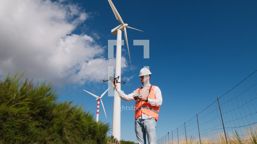 Engineer is using a drone to check wind power plant