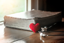 stethoscope on a Bible and small red heart 