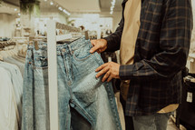 Young man in fashion store chooses things for himself - jeans.. 
