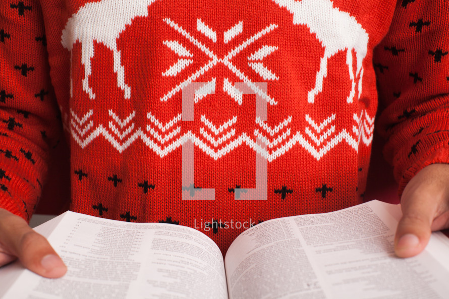 woman in a Christmas sweater reading a Bible 