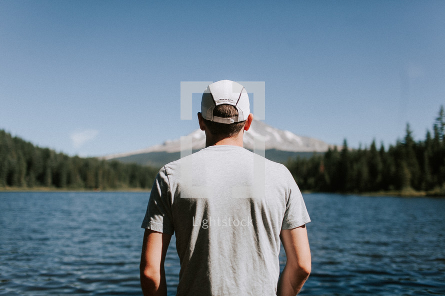 man looking out at a mountain lake 