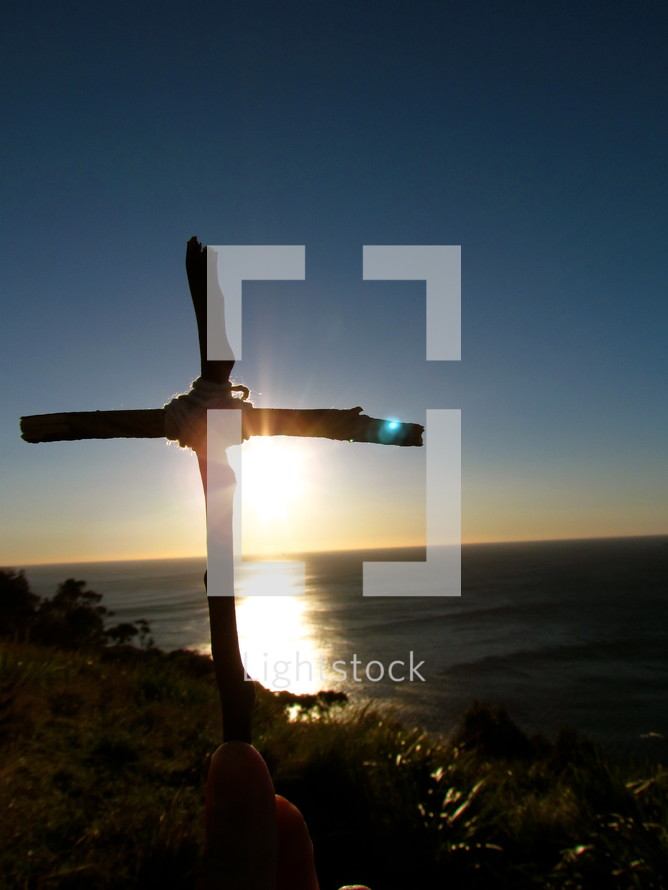 Silhouette of a cross with sunset on the water.