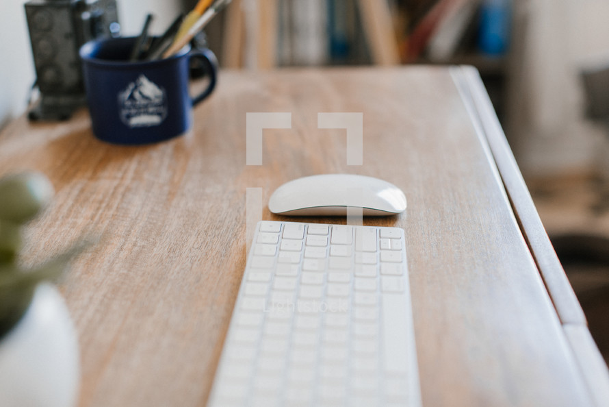 computer keyboard and mouse on a wooden desk 