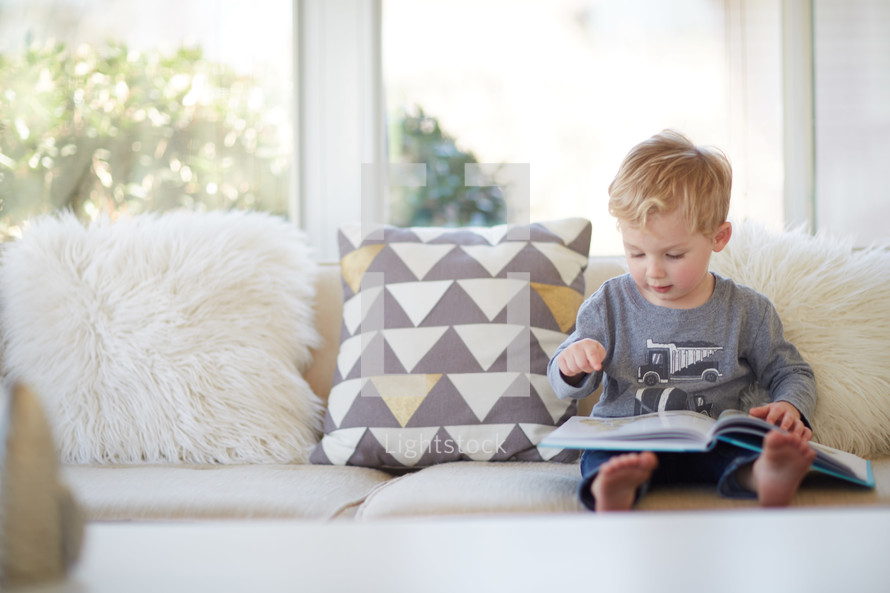a toddler boy reading a book 