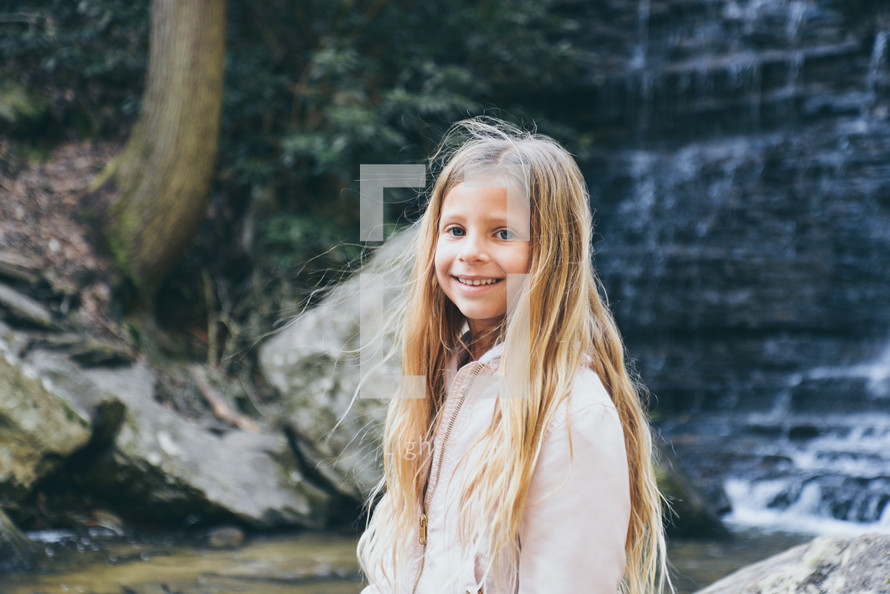 smiling child in front of a waterfall 