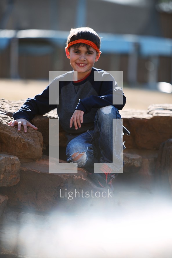 a child smiling sitting outdoors 