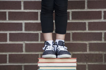 a student standing on a stack of books 