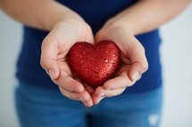 a woman holding a red heart in cupped hands 