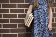 a little girl holding a stack of books 