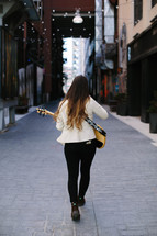 woman walking playing a guitar 