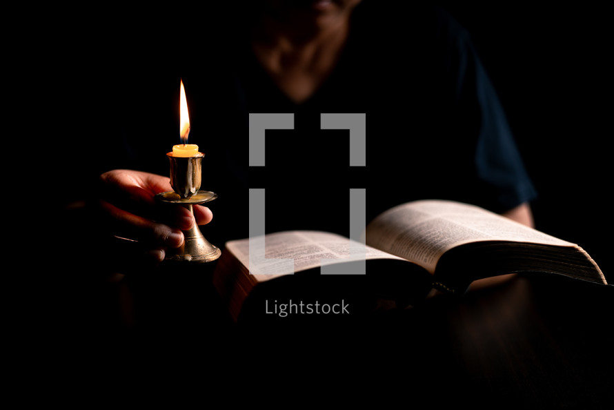 Bible and candlelight with studying woman