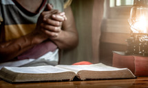 senior woman with praying hands over a Bible 