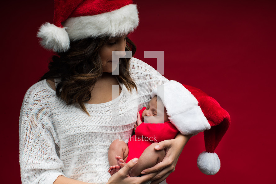 a mother in a santa hat holding a newborn 