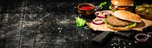 A burger on a stone board on a table. On a black background. High quality photo