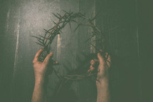 arms holding up a crown of thorns 
