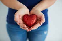 a woman holding a red heart in cupped hands 