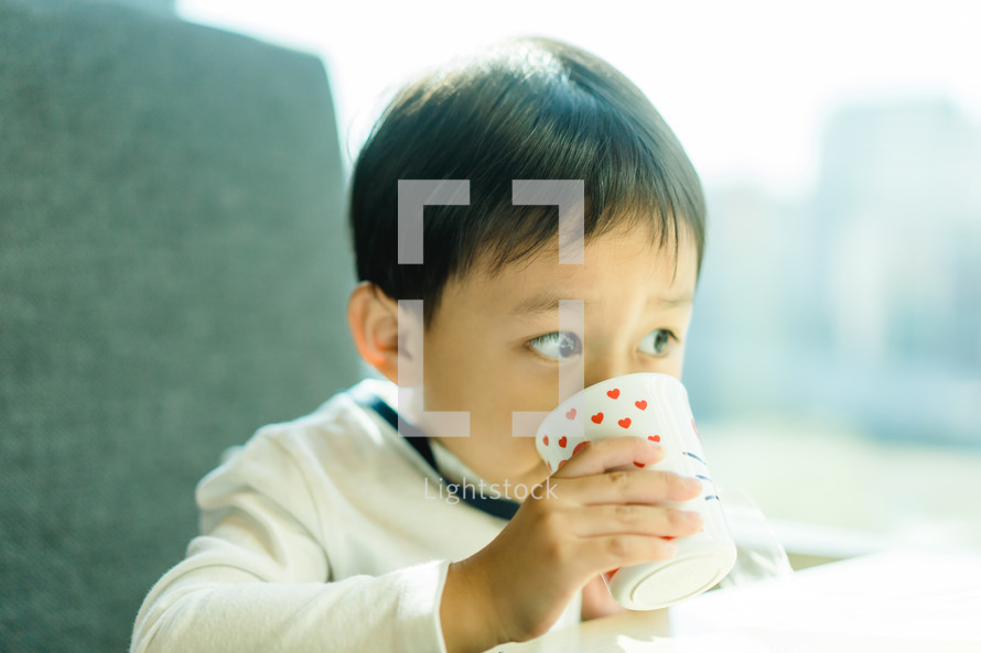 a toddler drinking out of a cup 