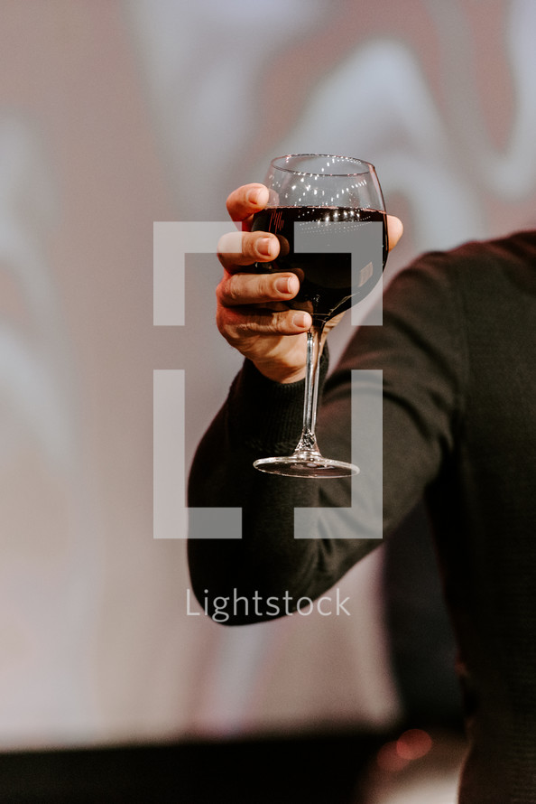Man holding up a glass of wine during communion. 