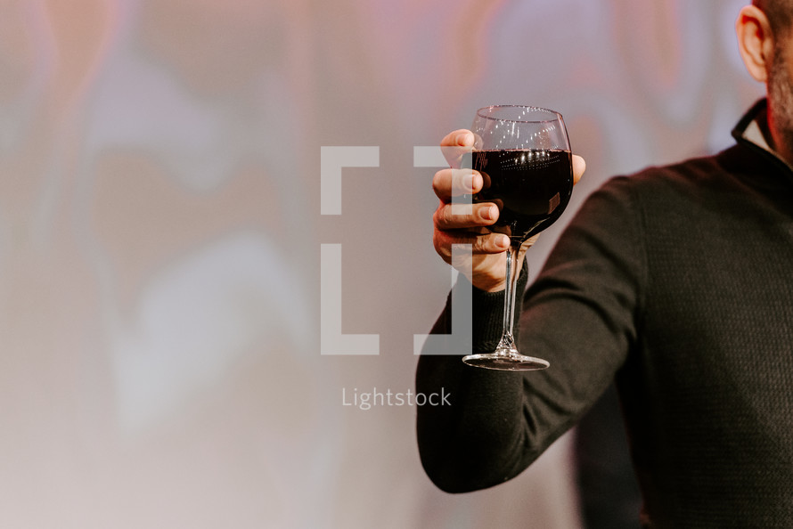 Man holding up a glass of wine during communion.