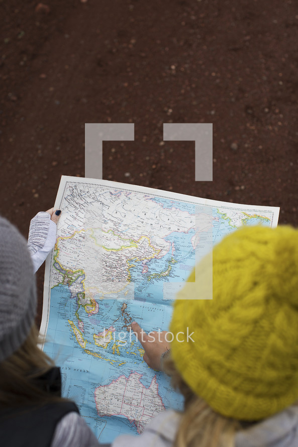 Two women in winter hats looking at a map.