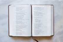 A bible turned to Proverbs on a white marble counter top