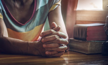 senior woman with praying hands on a table 